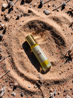 Divine Dew Lip Oil by Savage Balms laid on a sandy, natural background