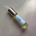 Small lip oil bottle with a gold cap and white label on a beige surface, labelled "Divine Dew Lip Oil" by Savage Balms