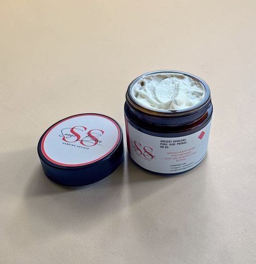 Savage Balms' Organic Beef Tallow Balm jar with its lid to laying on its right side, against a gentle, warm beige background.